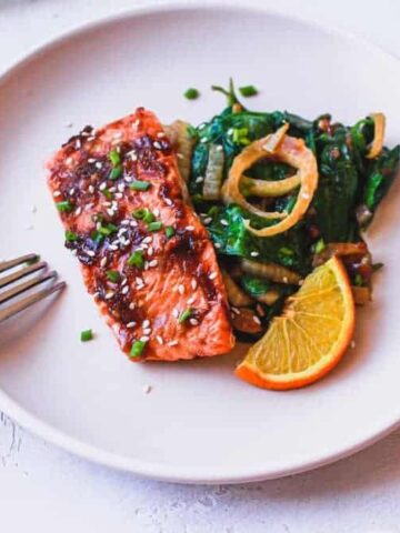 ginger soy salmon with sauteed spinach on a plate with a fork
