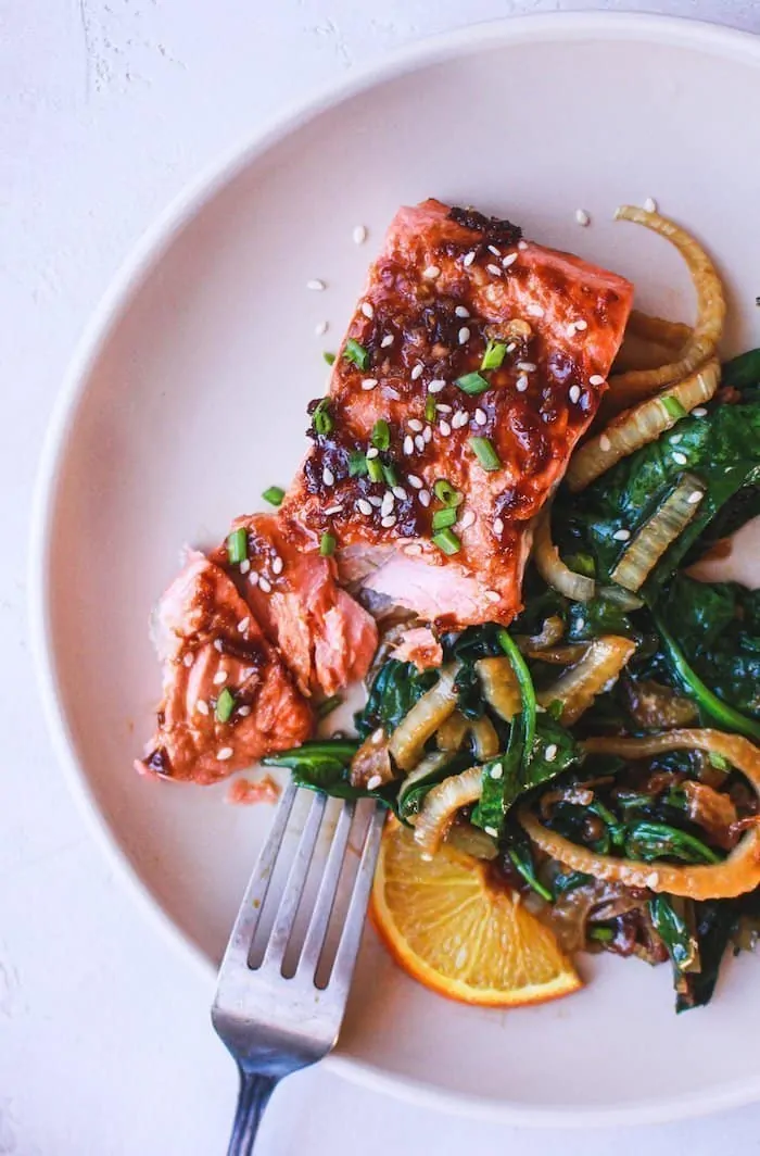 overhead of ginger soy salmon on a plate with sauteed spinach and fennel