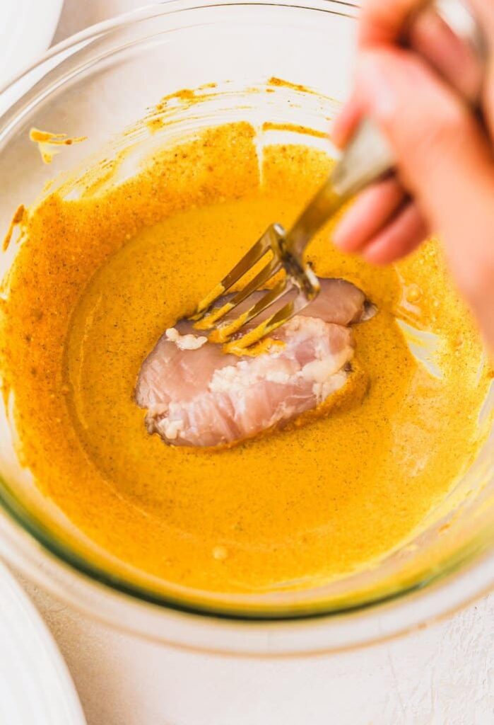 dipping chicken thighs into chicken shawarma sauce