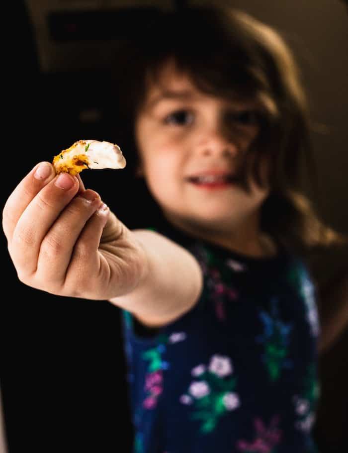 toddler holding a dipped jicama fry