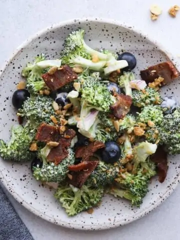 keto broccoli salad with bacon on a plate with a blue napkin and fork