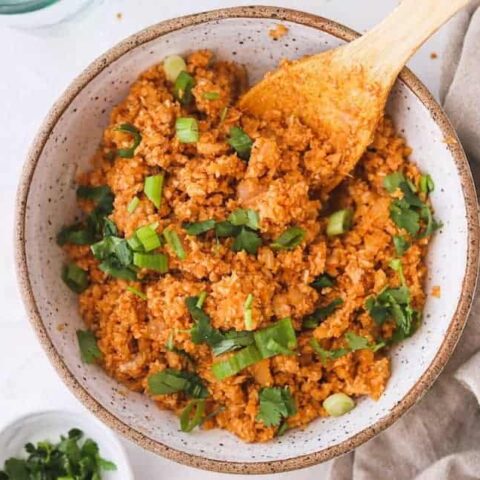 spanish cauliflower rice in a bowl with a spoon and linen