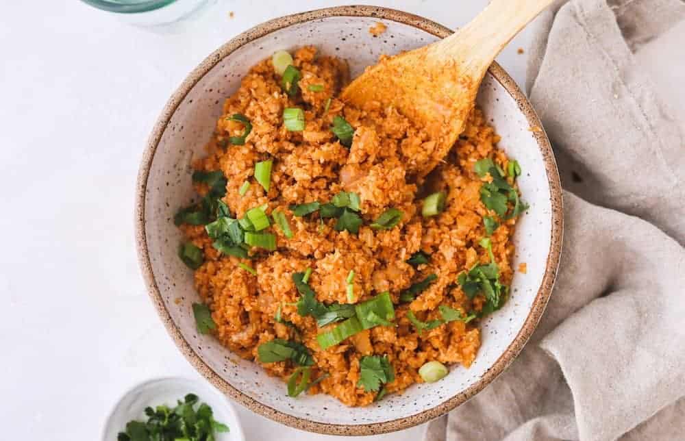 spanish cauliflower rice in a bowl with a spoon and linen