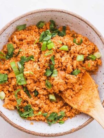 spanish cauliflower rice in a serving bowl with wooden spoon