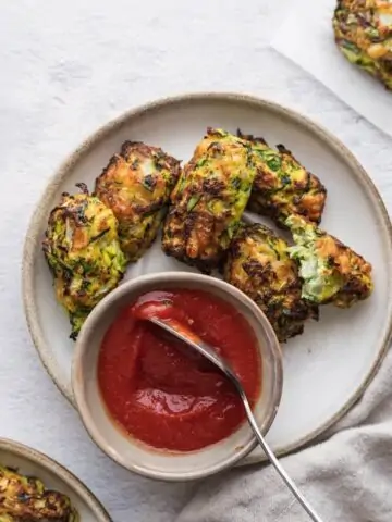 air fryer zucchini tots on a plate with ketchup and spoon