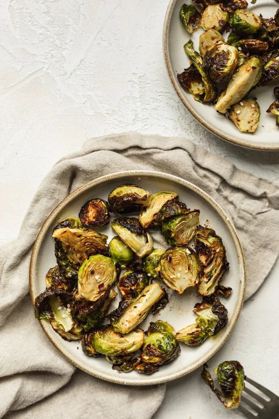 two plates with air fryer brussels sprouts and a fork