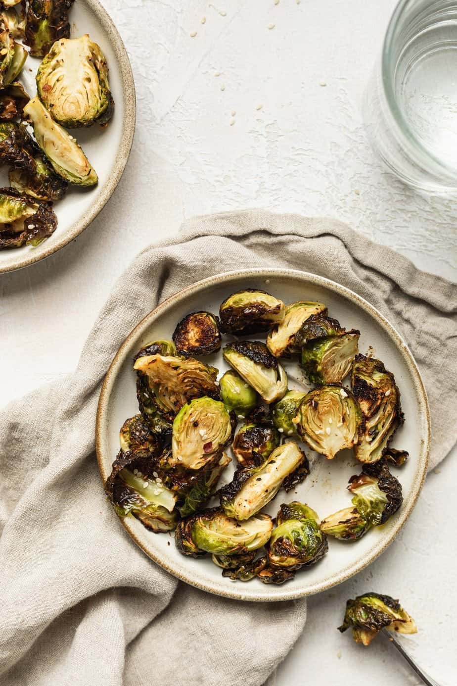 overhead of keto air fryer brussels sprouts with a fork and water glass