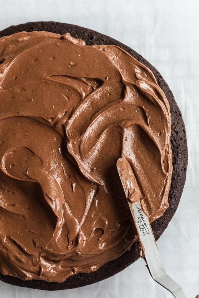 spreading frosting on keto chocolate cake