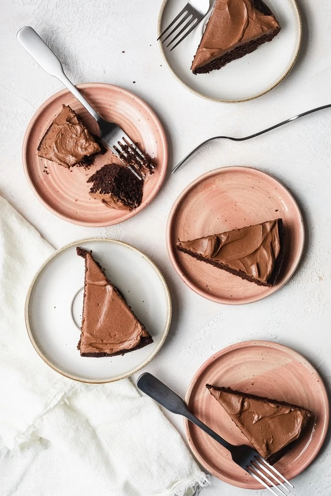 Keto chocolate cake slices on pink and white plates with forks. 