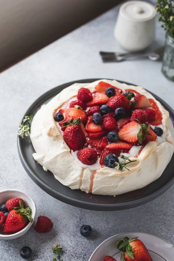 Keto pavlova with berries on a cake stand.