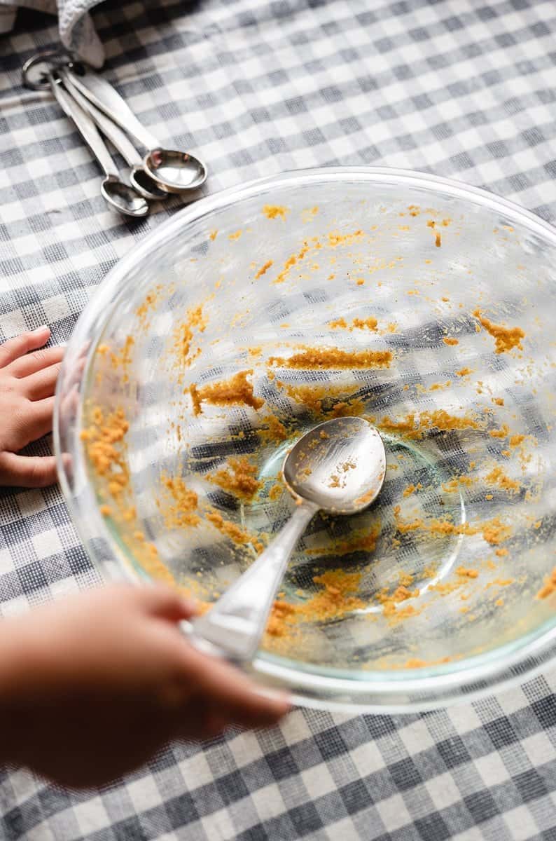 toddler holding spoon in dirty mixing bowl