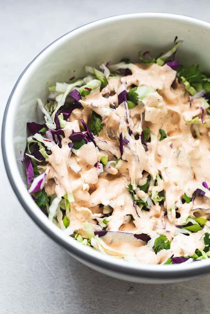 spicy keto coleslaw in mixing bowl with chipotle crema on top