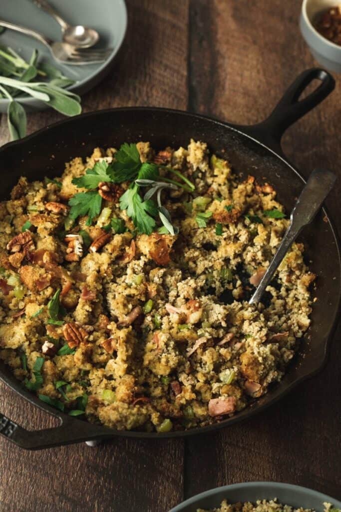 scooping out keto cornbread stuffing from cast iron skillet