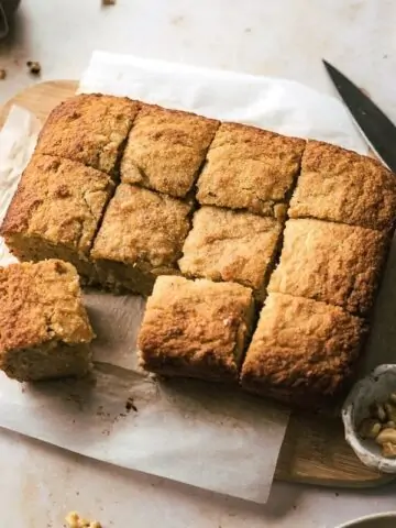 keto banana bread on cutting board with cups and knife