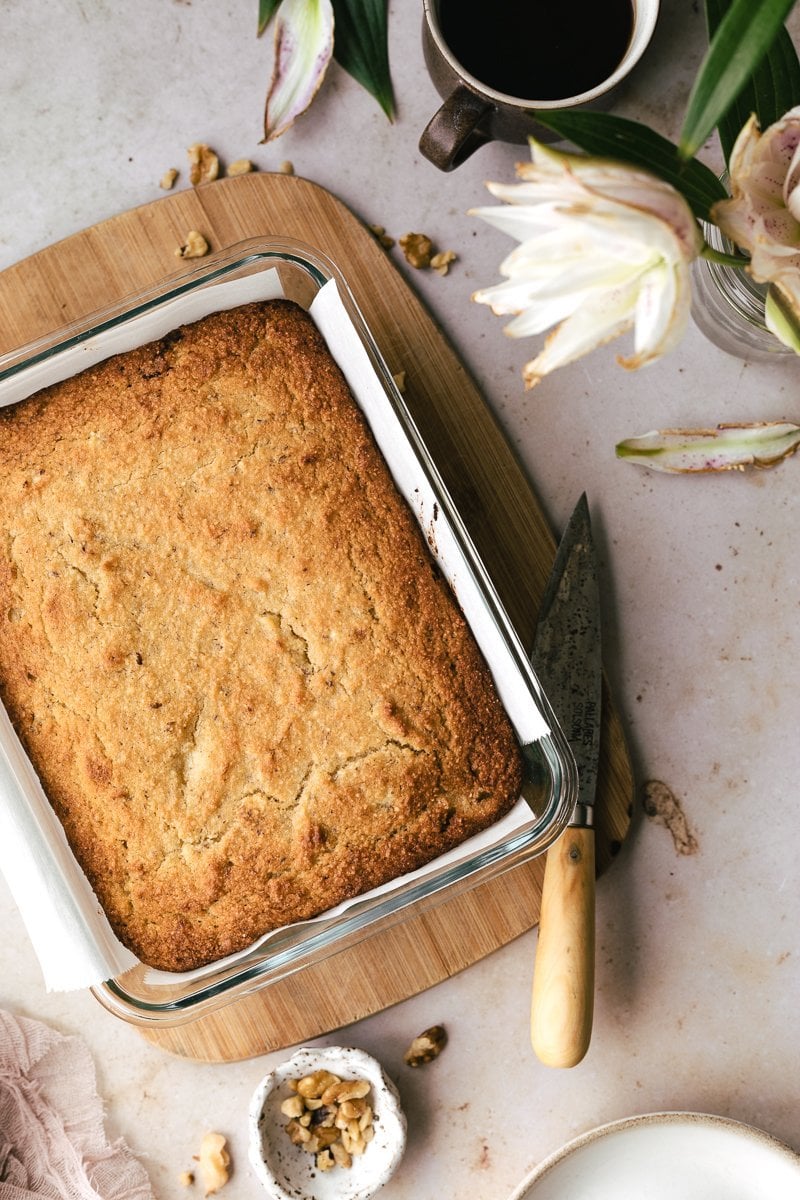 Keto banana bread in baking dish with florals and coffee.