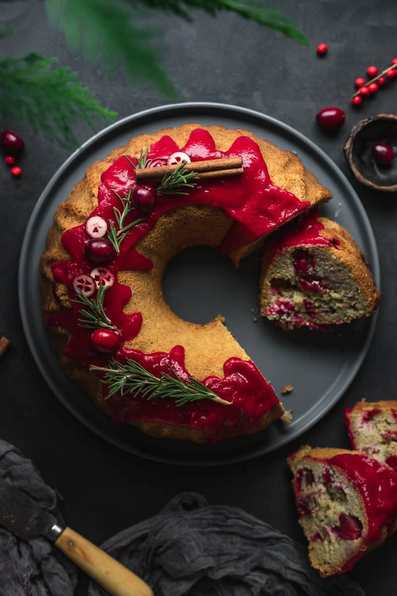 flatlay of keto cranberry Bundt cake with berries and rosemary on top