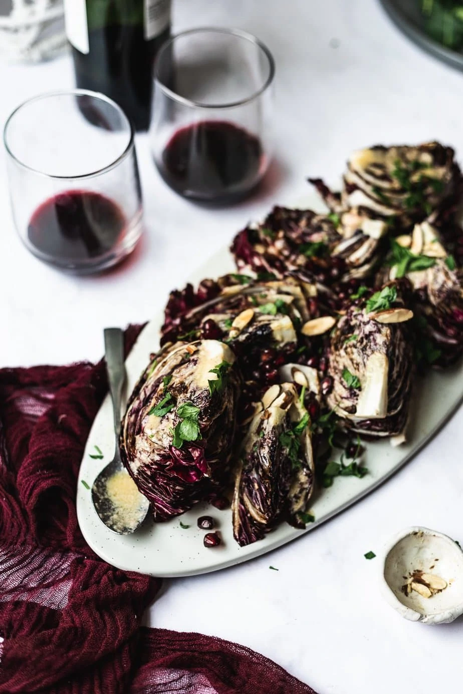 radicchio wedge salad on platter with dressing and wine glasses
