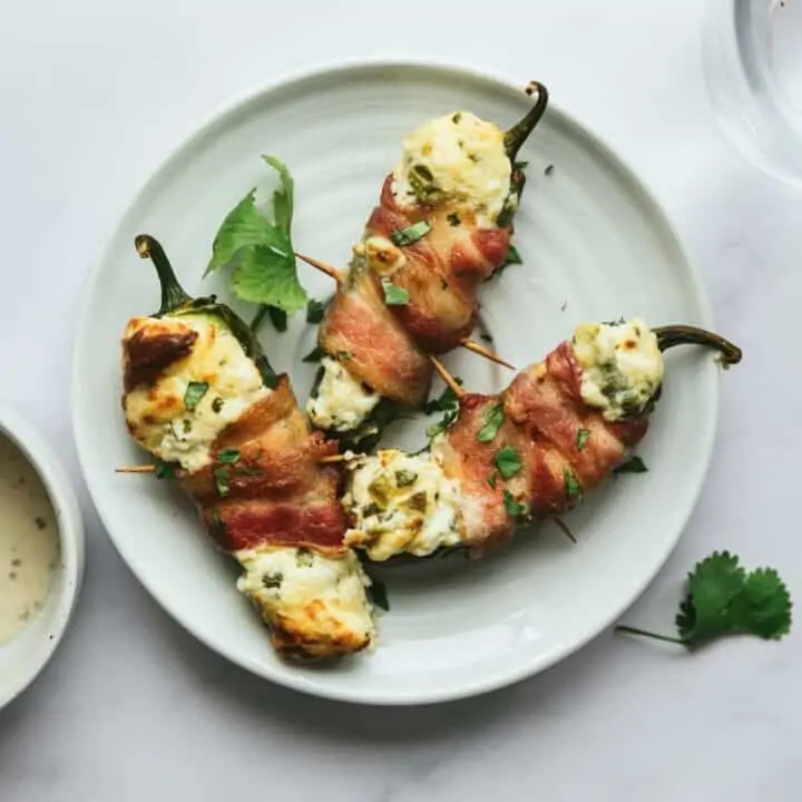 three bacon-wrapped jalapeño poppers on a plate