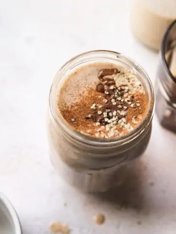 banana almond butter smoothie in a glass with toppings