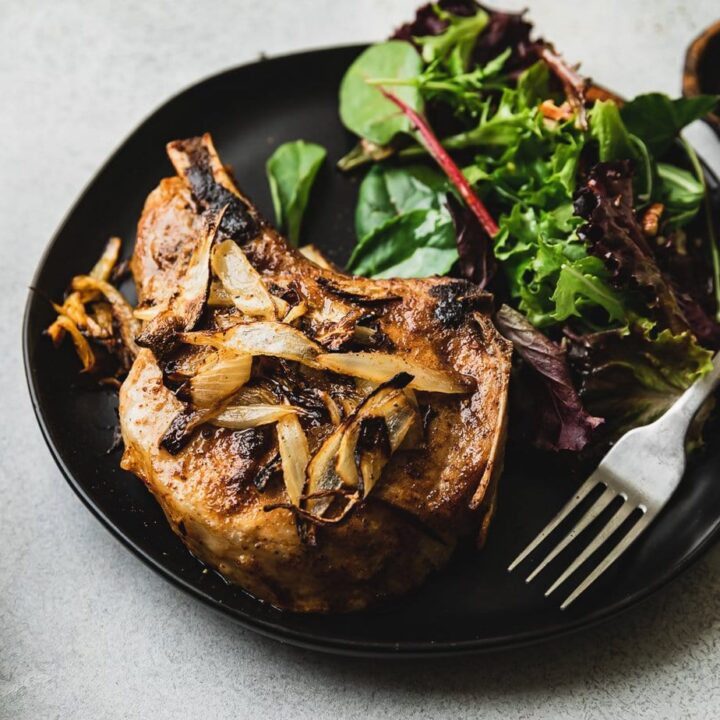 prepared air fryer pork chop with fork and salad on plate