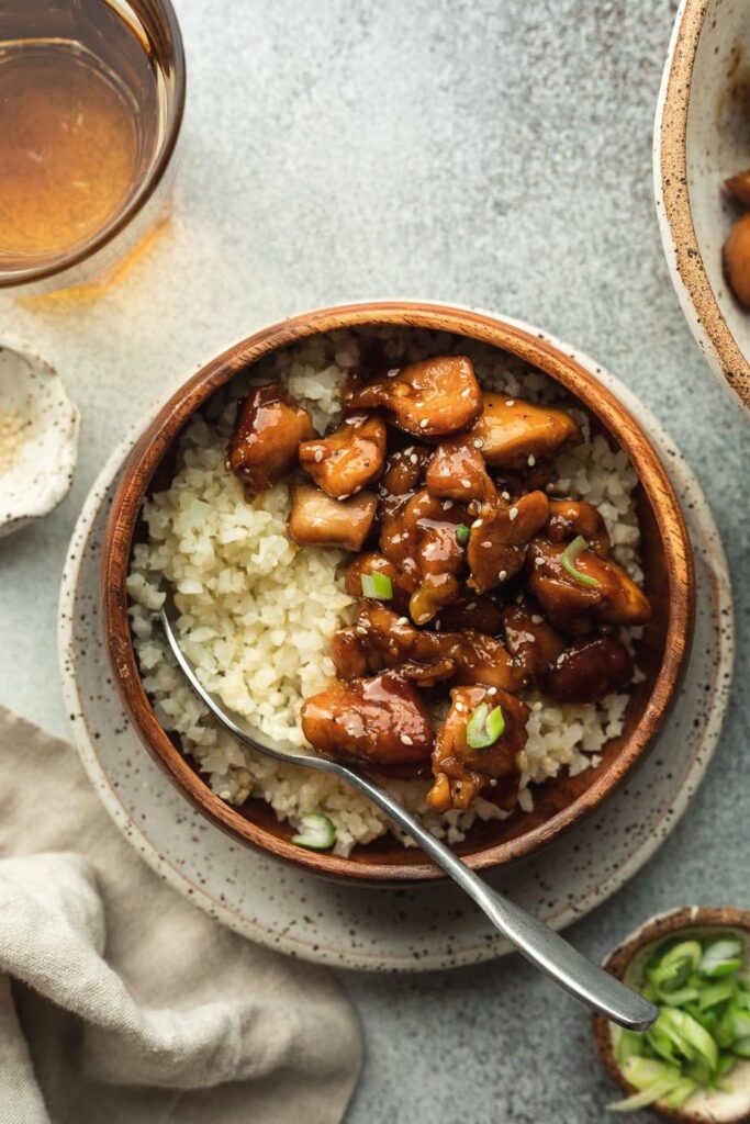 keto bourbon chicken with cauliflower rice in a bowl with a spoon