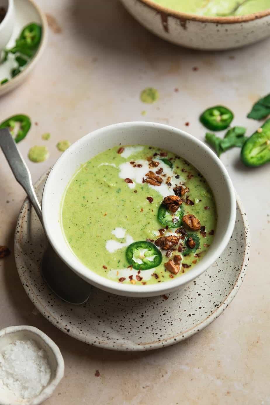 Spicy broccoli soup in a serving bowl with jalapeños next to it. 