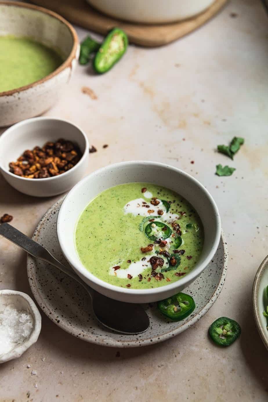 Spicy broccoli soup with jalapeño in a serving bowl on a marble surface. 