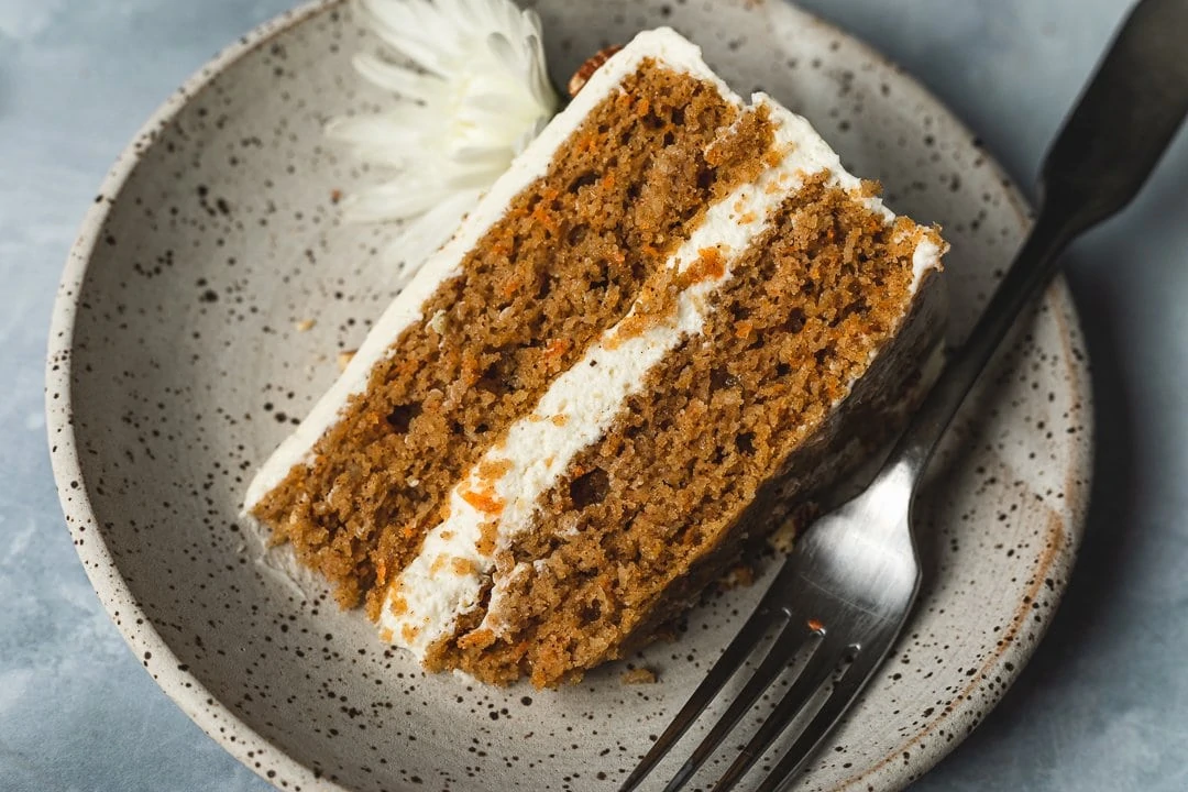 Slice of decorated keto carrot cake on a plate with a fork