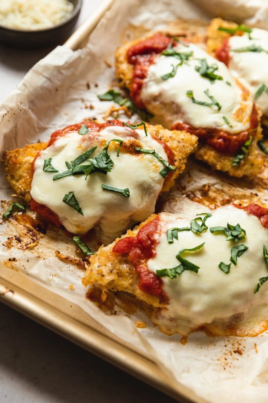 Pieces of keto chicken parmesan on a baking sheet. 