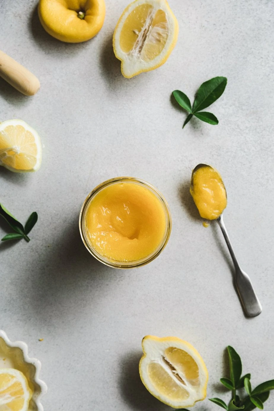 Sugar free lemon curd with halved lemons and green leaves.