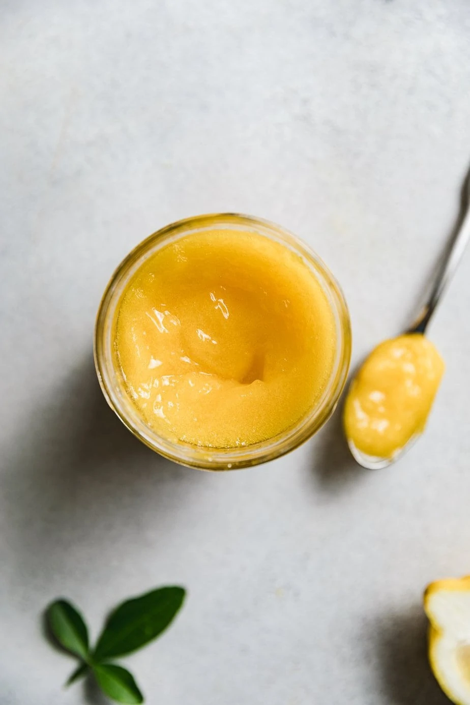 A jar of keto lemon curd with a spoon next to it. 