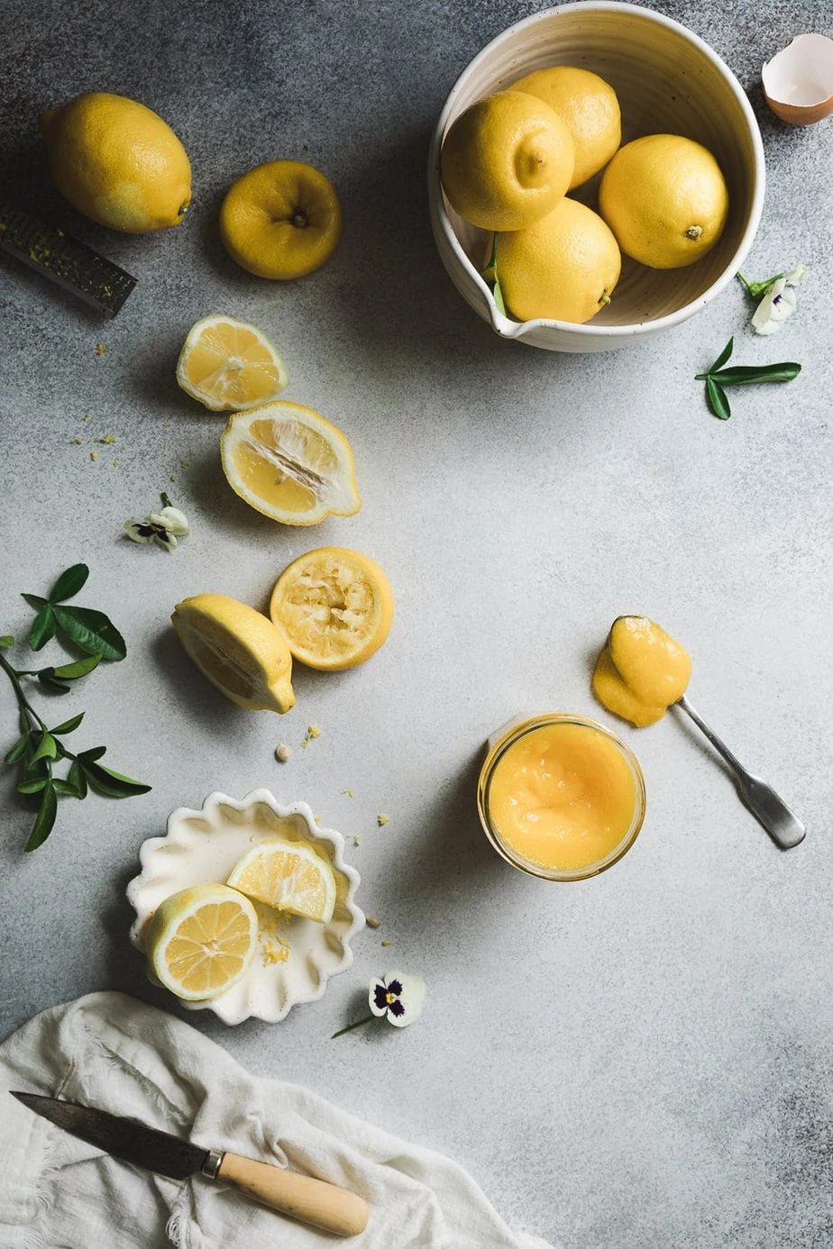 Keto lemon curd in a jar with lemons next to it.