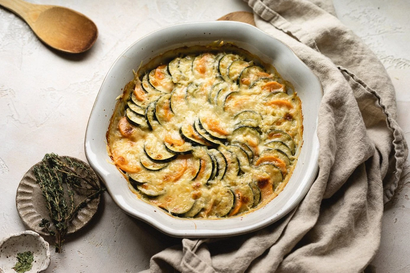 baked low-carb zucchini gratin with fresh thyme and a linen napkin