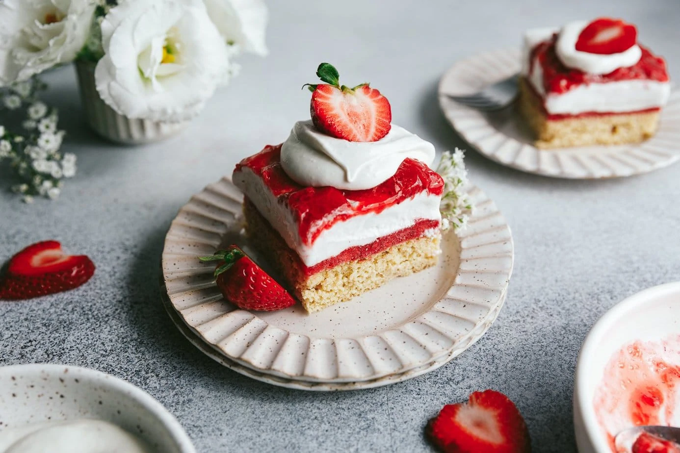 keto strawberry shortcake ice cream cake on stacked saucers topped with berries and whipped cream