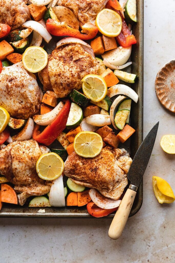 raw chicken pieces and vegetables on a sheet pan