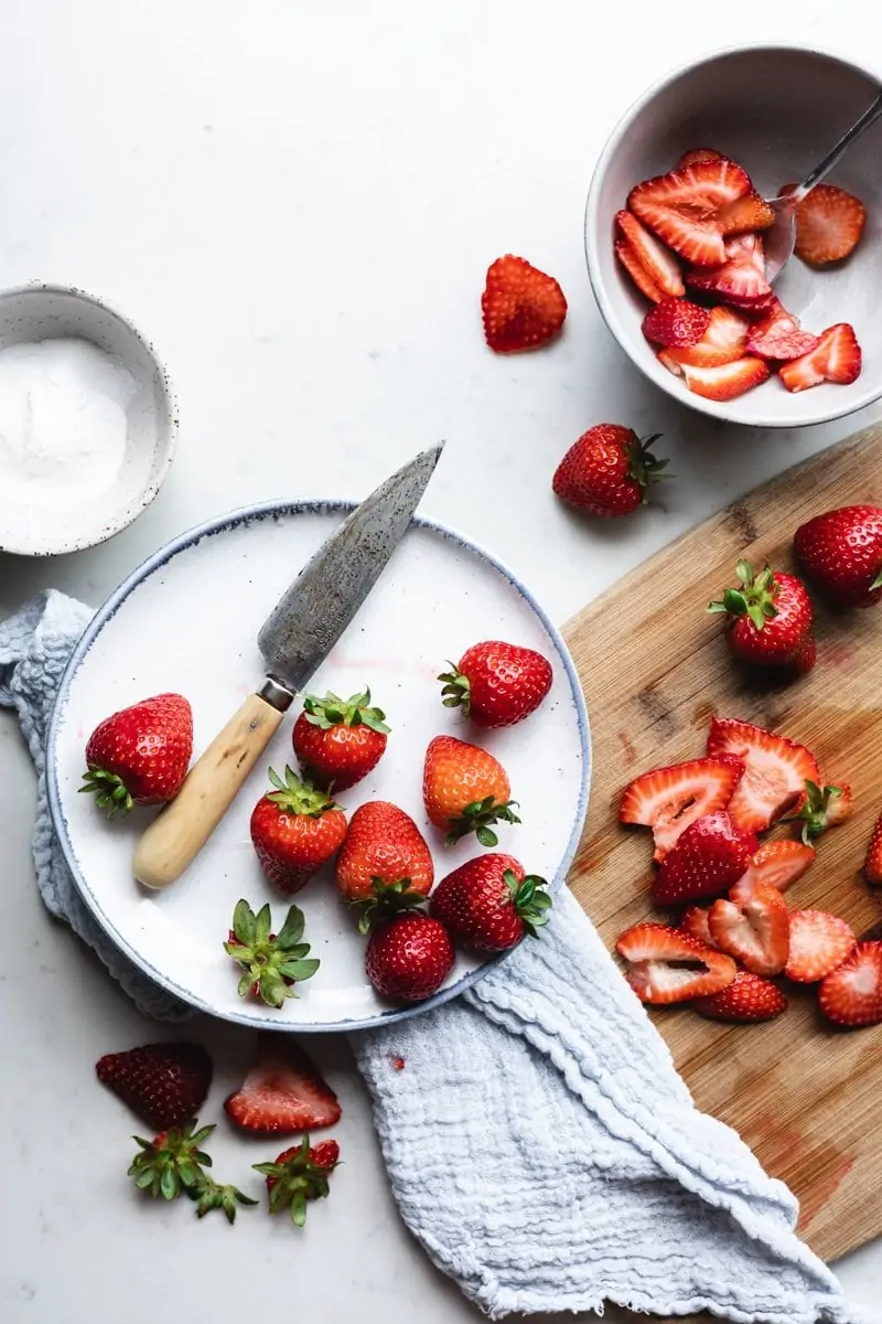 flatlay of strawberries on cutting board with knife and plate