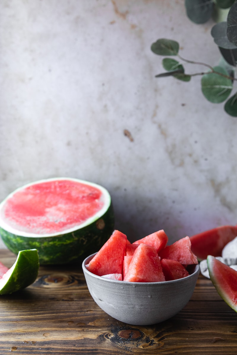 bowl of cubed watermelon with half a watermelon next to it