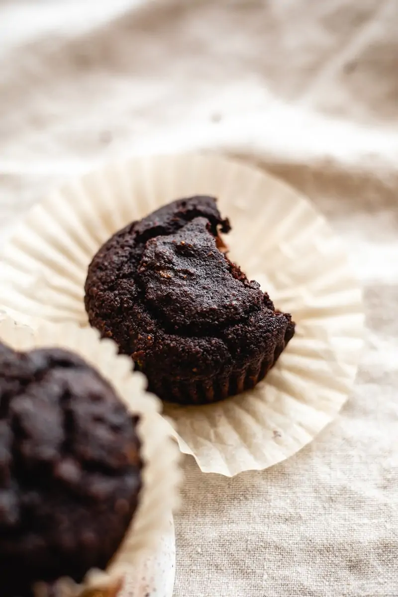 one single gluten free chocolate zucchini muffin on a linen cloth