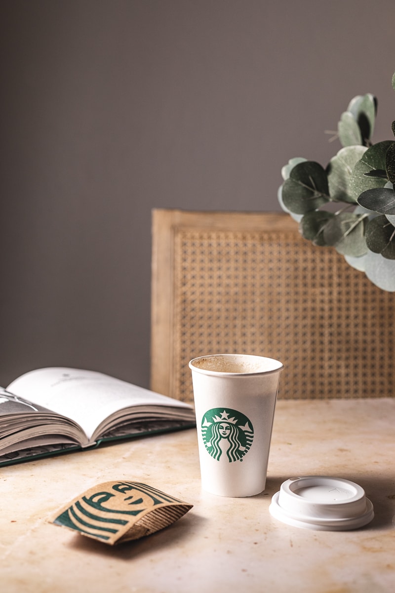 Low-carb Starbucks drink on a table with a chair and a book.