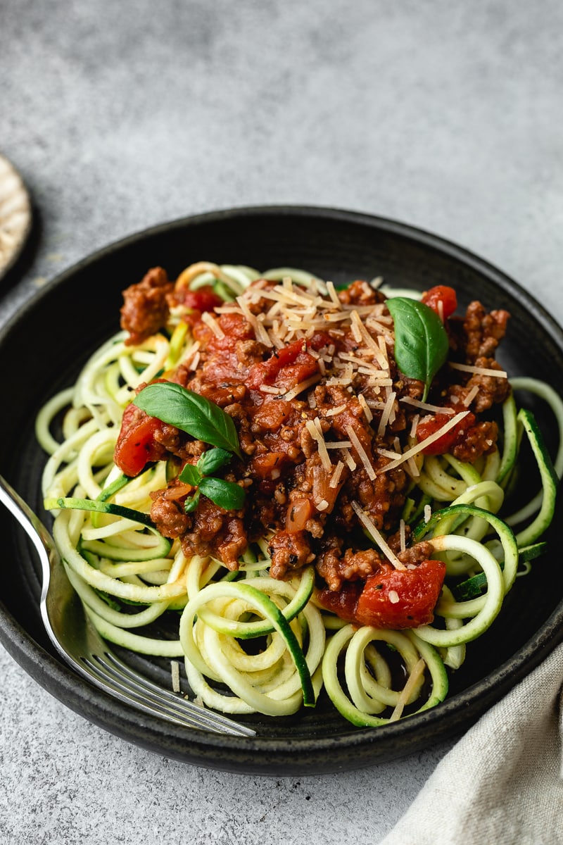 Keto spaghetti sauce served on zoodles with freh basil leaves.