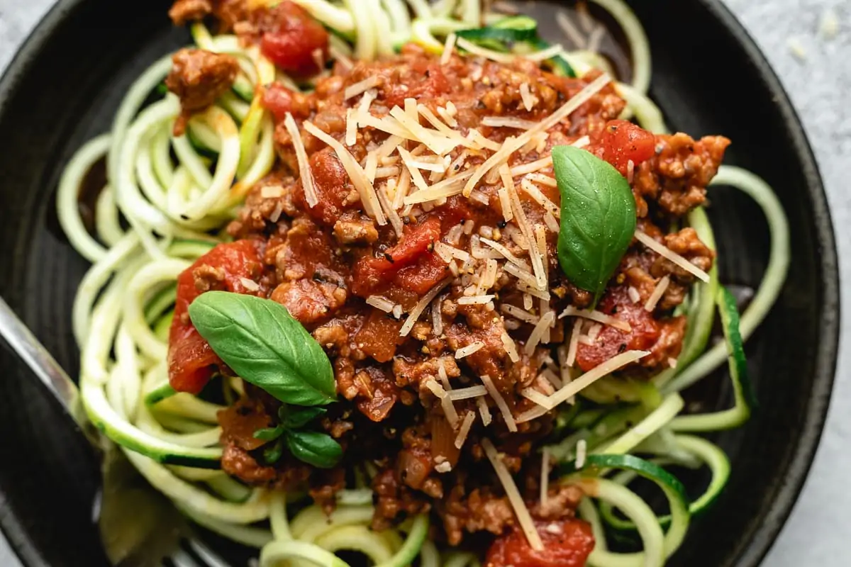 Closeup of keto spaghetti sauce on zoodles garnished with Parmesan and basil.