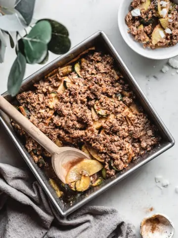 keto and gluten-free apple crisp in baking dish with napkin and wooden spoon