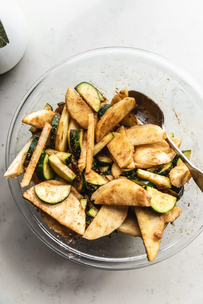 apples and zucchinis tossed with cinnamon in a bowl