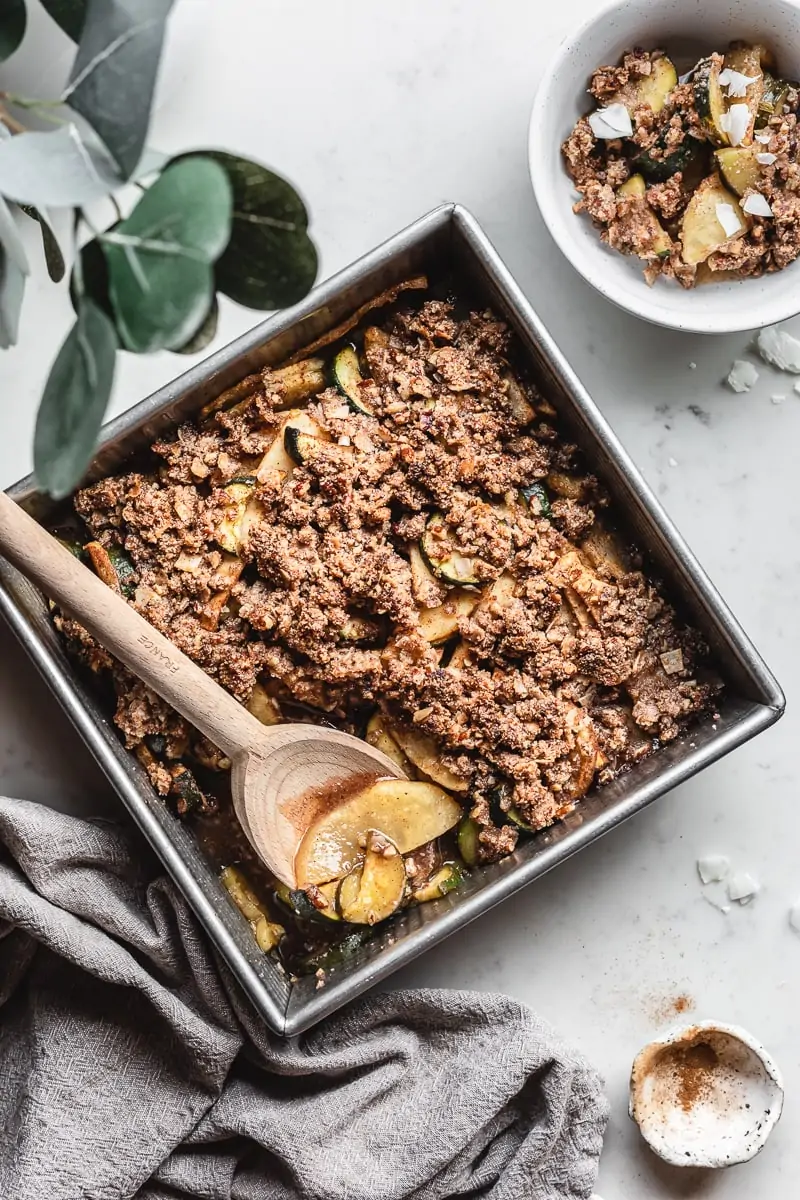 keto apple zucchini crisp with a wooden spoon in a baking pan