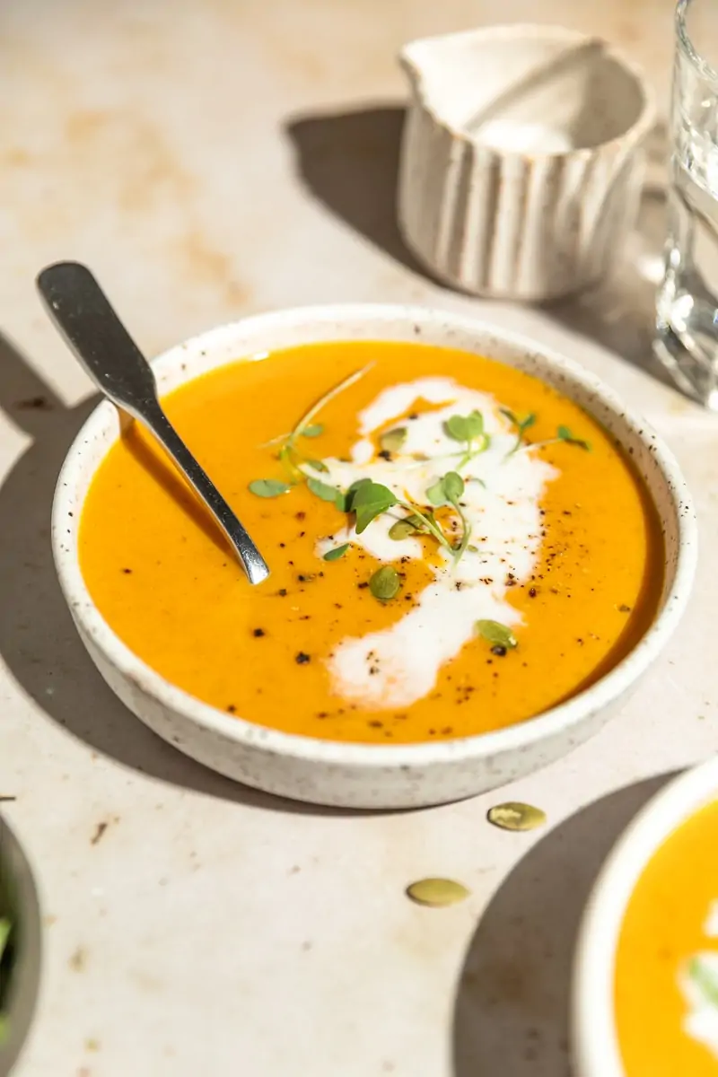 keto pumpkin soup with coconut cream and a glass of water