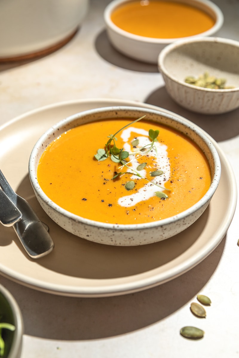 Keto pumpkin soup with coconut milk swirled on top. 