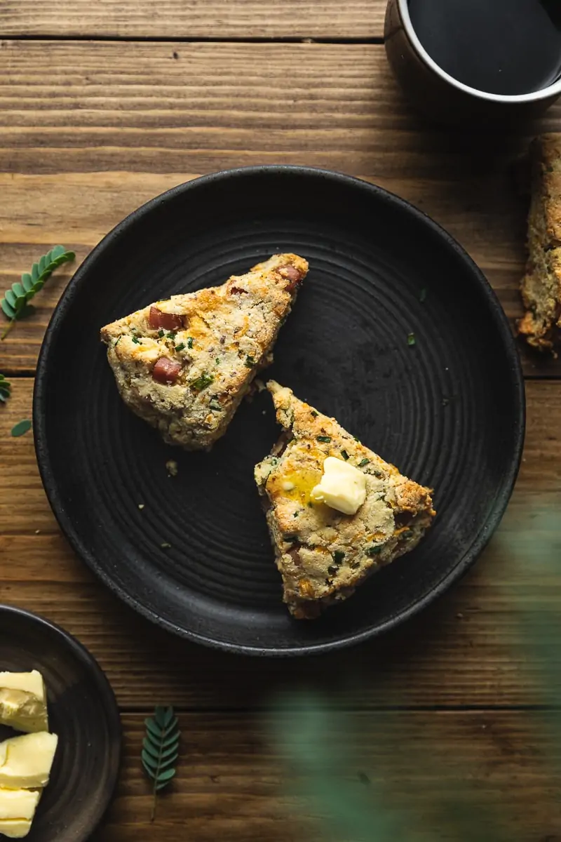 Almond flour scones on a black plate with a cup of coffee.