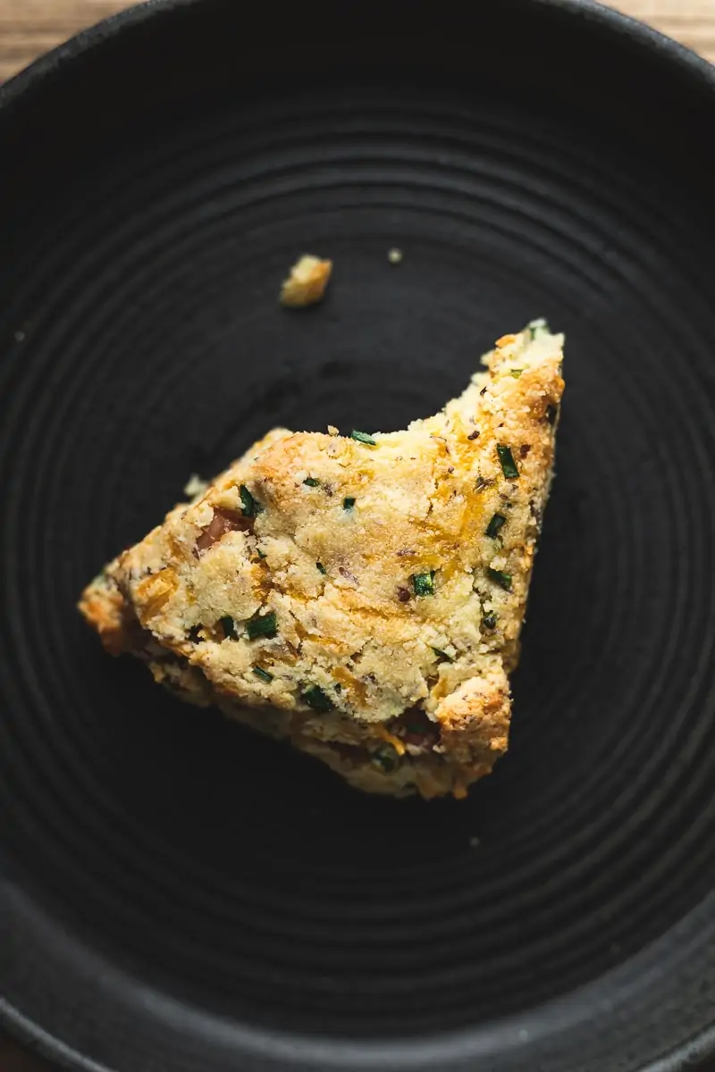 One savory almond flour scone on a black plate.