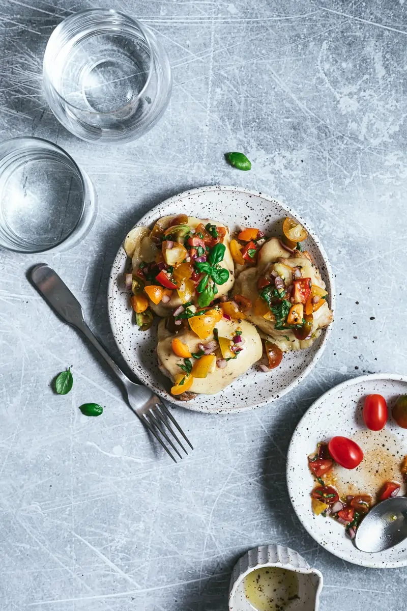 Bruschetta chicken bake on plates with a fork and fresh basil.