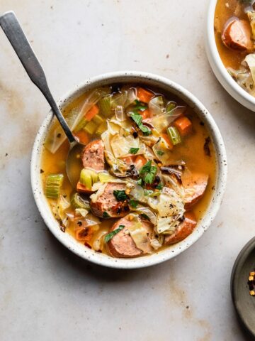 cabbage sausage soup in a bowl on a marble surface